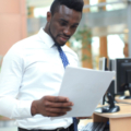 African American reading paper at workplace, looking at financial document