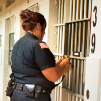 A corrrections officer in navy blue uniform uses keys to open a prison cell. Source: AFSCME Stillwater-Wisconsin Photo by Nancy-Hauck