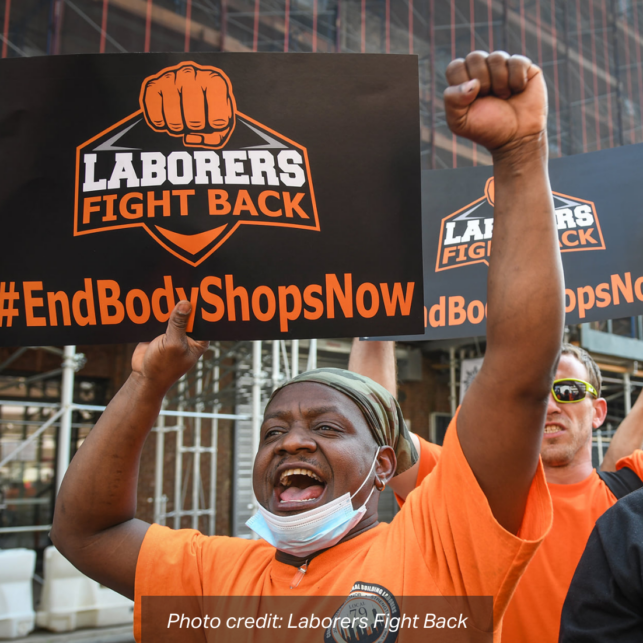 A Black man worker advocate raises a fist while marching with other workers carrying signs that read: "Laborers Fight Back, #EndBodyShopsNow". photo credit: Laborers Fight Back