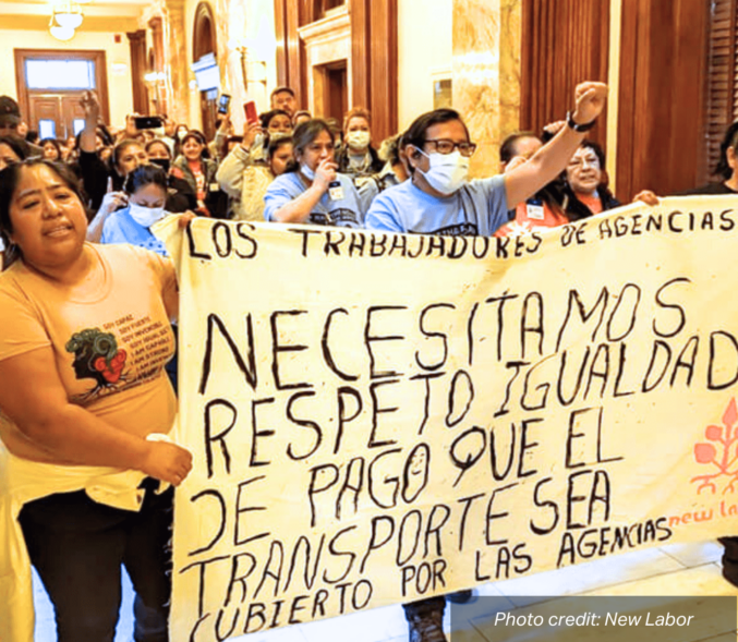 New Labor mambers march holding a sign that reads: "Los Trabajadores De Agencias - Necesitamos Respeto Igualidad De Pago Que El Transporte Sea Cubierto Por Las Angencias". photo credit: New Labor