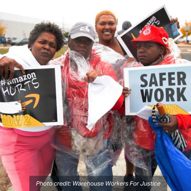 A group of four Black women wear ponchos outdoors, holding signs that read: "#Amazon Hurts MDW2, and Safer Work". photo credit: Warehouse Workers For Justice