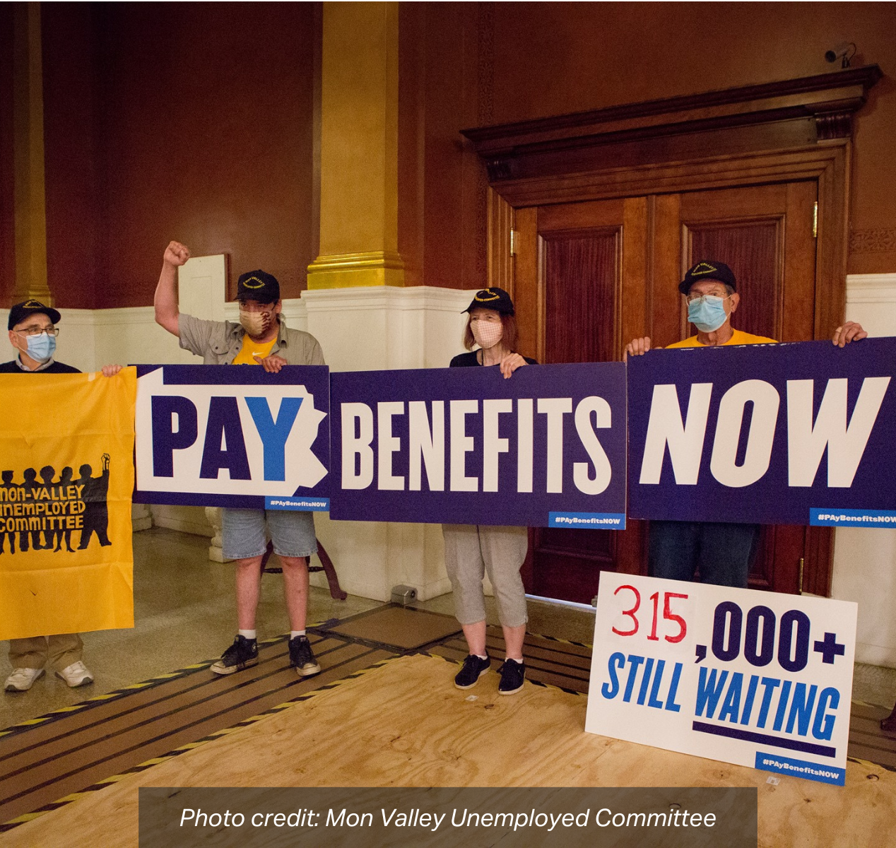 A group of advocates hold up a sign in front of the Governor's Office that reads: "Pay Benefits Now, 315,000+ Still Waiting". photo credit: Mon Valley Unemployed Committee