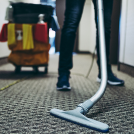 A cropped image of a housekeeper vacumming a hallway